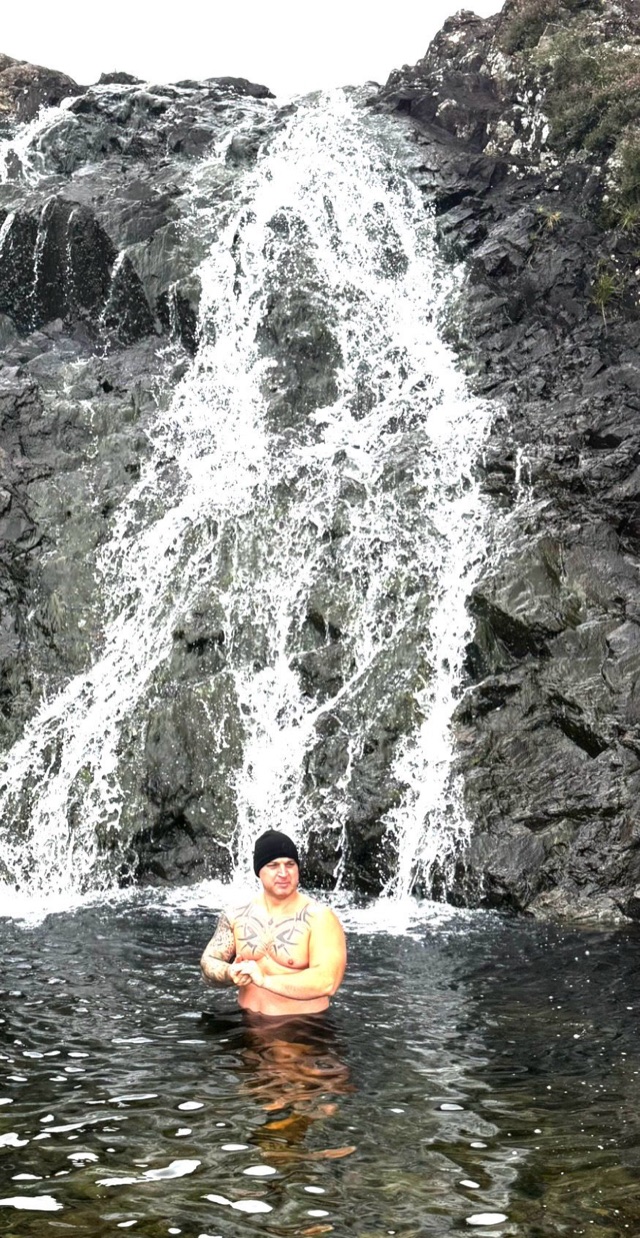 Craig standing in cold water in front of a waterfall